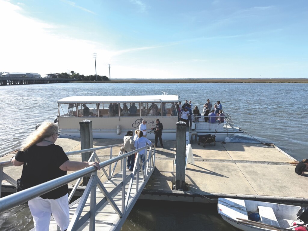 a water ferry filled with people is in the ocean at a doc where more people are loading